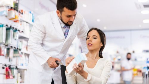 Barrierefreie Reise vorbereiten: Rollstuhlfahrerin fragt Apotheker nach einem Medikament. Barrierefreie Reise vorbereiten: Rollstuhlfahrerin fragt Apotheker nach einem Medikament.